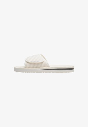 Sandale à glissière beige clair avec une tige à nervures, une sangle rembourrée et une bande sombre contrastante sur la semelle. Semelle en caoutchouc texturé pour une meilleure adhérence.