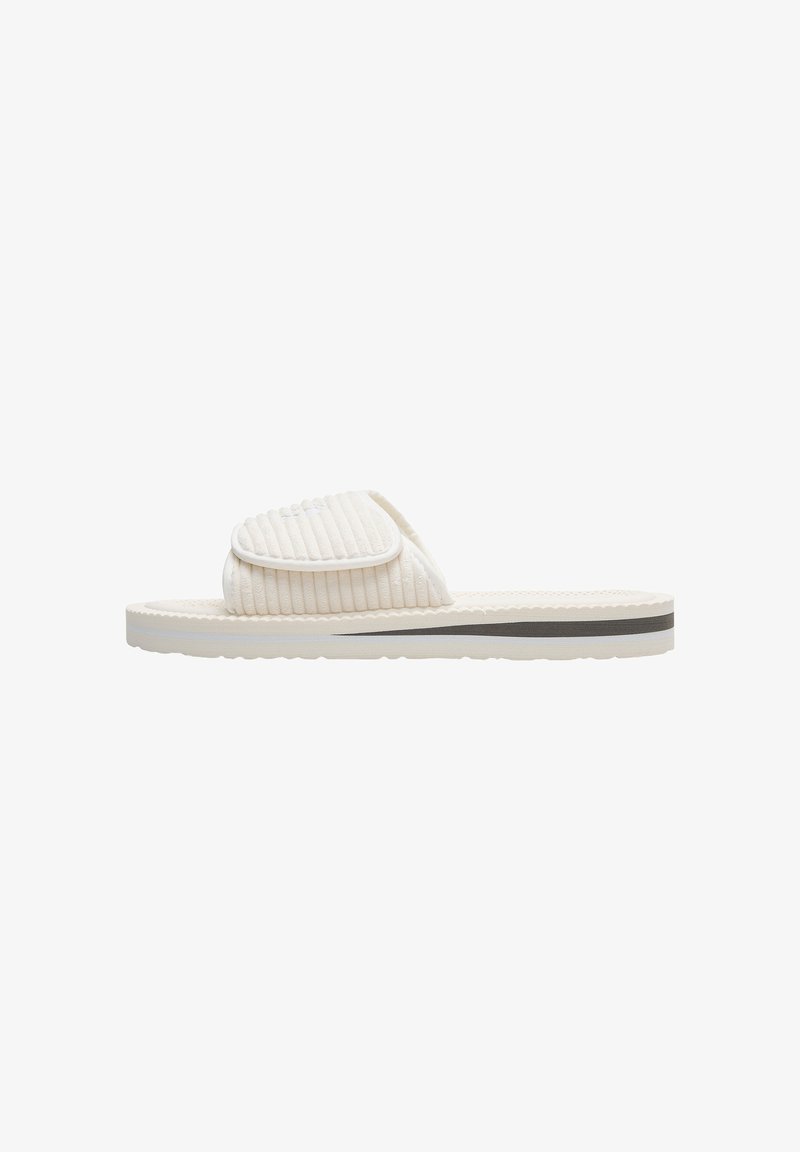 Light beige slide sandal with a ribbed upper, padded strap, and a contrasting dark stripe on the sole. Textured rubber sole for grip.
