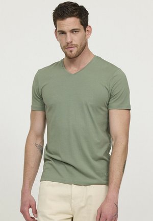 T-shirt vert à col en V fabriqué en coton doux, design ajusté, manches courtes, avec un petit logo près de l'ourlet.