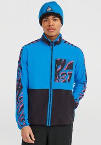 Letvægts zip-up jakke i lys blå med sorte detaljer. Har mønstrede ærmer og en frontlomme med lynlås. Blød stofstruktur.