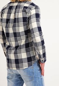 Geruite flanellen overhemd in marineblauw en crèmekleur, met lange mouwen, een kraag en een knoopsluiting. Licht gestructureerde stof.