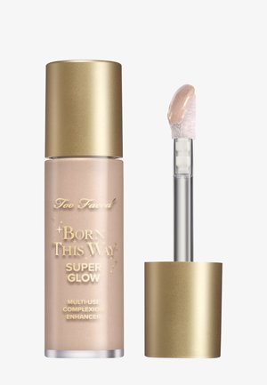Too Faced Born This Way Super Glow teintversterker in een parelachtige roze fles met een gouden dop en een doorzichtige applicatorstift.