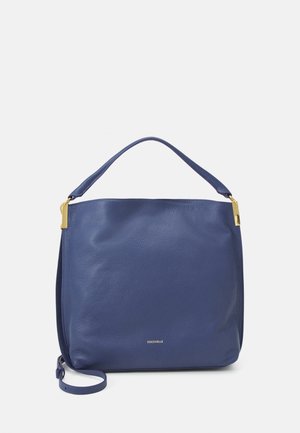 Niebieska skórzana torebka z pojedynczym uchwytem u góry, akcentami w kolorze złotym oraz odłączanym paskiem na ramię, pokazana na jasnym tle.