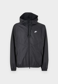 Μαύρο αδιάβροχο μπουφάν Nike με κουκούλα, εμπρόσθιο φερμουάρ, κορδόνια ρύθμισης, ελαστικά μανίκια και λευκό λογότυπο στο αριστερό στήθος.