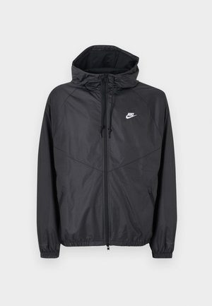 Jachetă de vânt Nike neagră cu glugă, fermoar frontal, șnururi de ajustare, manșete elastice și logo alb pe partea stângă a pieptului.
