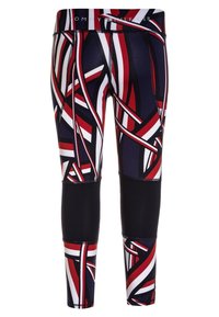 Legginsit, joissa on rohkea geometrijainen kuvio punaisena, valkoisena ja tummansinisenä. Valmistettu joustavasta kankaasta, ja nilkkojen lähellä on musta paneeli.