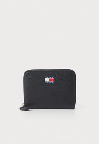 Black textured leather wallet with a zipper closure and a small rectangular Tommy Jeans logo in red, white, and blue on the front.
