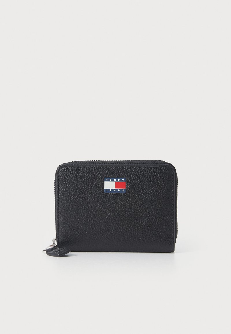 Black textured leather wallet with a zipper closure and a small rectangular Tommy Jeans logo in red, white, and blue on the front.