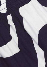 Tissu de ceinture élastique noir et blanc avec des larges rayures verticales alternées et une texture froncée.