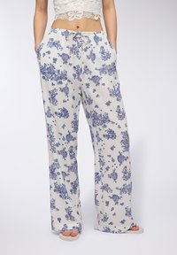 Pantaloni floreali con vestibilità ampia realizzati in tessuto leggero, con uno sfondo bianco e motivi floreali blu, vita elastica e tasche laterali.