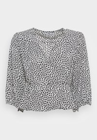Blusa bianca e nera con un motivo a vortice, maniche lunghe a sbuffo, scollatura rotonda e orlo arricciato. Tessuto leggero.