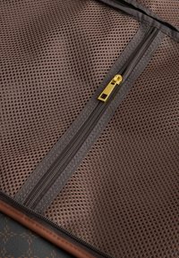 Material din plasă maro cu o suprafață texturată. Dispune de două fermoare, unul auriu, oferind un element de design funcțional.