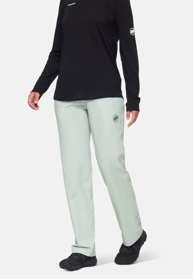 Licht mintgroene broek gemaakt van lichte stof, met een fitted ontwerp en een logo-accent op de dij. Gecombineerd met een zwart shirt met lange mouwen.