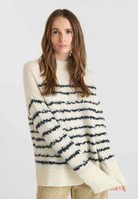 Maglione crema con strisce orizzontali nere, polsini e orlo a coste, realizzato in un morbido materiale testurizzato. Vestibilità rilassata con spalle scese.