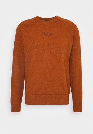 Oranssi pullover-huppari, joka on valmistettu teksturoidusta kankaasta. Siinä on pyöreä pääntie, pitkät raglanhihat ja pieni logo rinnassa.