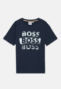 T-shirt en coton bleu marine avec col rond et manches courtes, arborant un texte "BOSS" usé en blanc et bleu clair sur le devant.