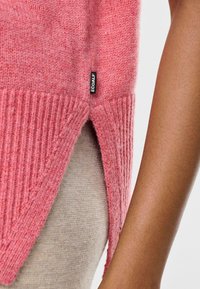 Pull en laine rose avec ourlet côtelé et fente latérale, arborant une petite étiquette noire Ecoalf. Texture lisse avec une coupe décontractée.
