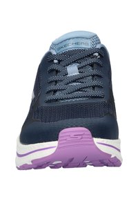 Marineblauwe sportschoenen met een bovenwerk van mesh, getextureerde veters en een paarse en witte zool. Bevat een versterkte neus en het merklogo op de tong.