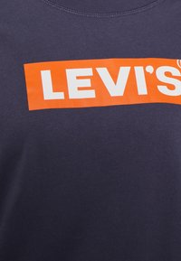 Felpa blu navy con un audace logo arancione Levi's in maiuscolo sul davanti. Collo rotondo e tessuto di cotone strutturato.