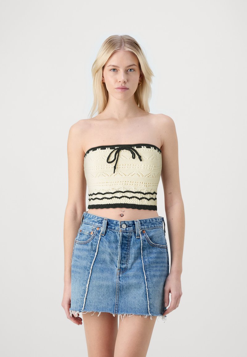 Häkelstil, cremfarbenes Bandeau-Top mit schwarzen Akzenten und vorn gebunden, kombiniert mit einem blauen Denim-Minirock mit ausgefranstem Saum und vorderen Nähten.