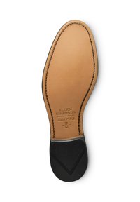 Suola di scarpa in pelle marrone con una superficie liscia, bordi arrotondati e tacchi in gomma nera. Dettagli del marchio incisi vicino al centro.