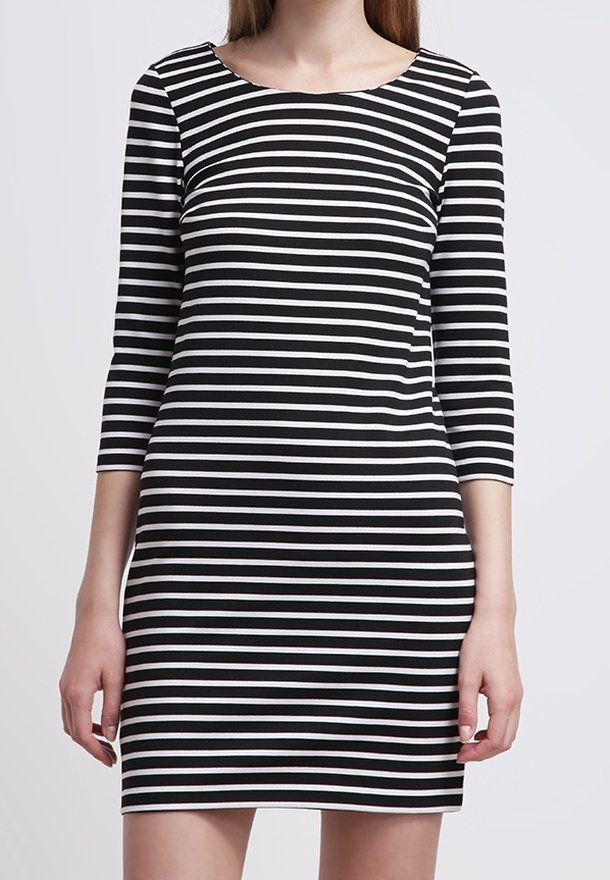 Robe rayée noir et blanc avec manches trois-quarts, encolure ronde, coupe ajustée et texture de tissu lisse. Sa longueur atteint le milieu de la cuisse.