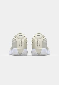 Lystfarvede sneakers til sport med en mesh-overdel, mønstrede detaljer og en gummisål. Har en tab med "001" på hælen.
