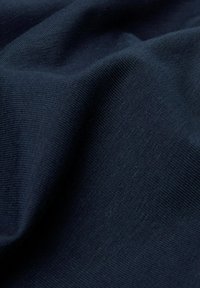 Dunkelblauer Stoff mit einer glatten, leicht strukturierten Oberfläche; weist ein feines geripptes Muster auf, um zusätzliche Dimension zu verleihen. Weiches und flexibles Material.
