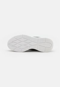 Black athletic shoe sole with a textured white rubber surface, featuring a grid pattern for grip and stability. Logo embossed on the side.