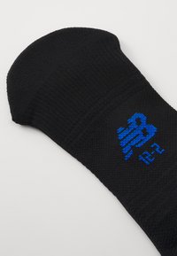 Svart strumpa med ribbat mönster, avrundad tå och en blå tryckt logotyp. Har en tätt vävd design för hållbarhet.