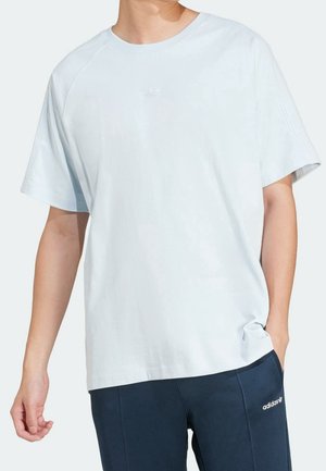 Personne portant un t-shirt à manches courtes bleu clair uni et un pantalon Adidas bleu foncé avec un logo blanc sur la cuisse gauche.