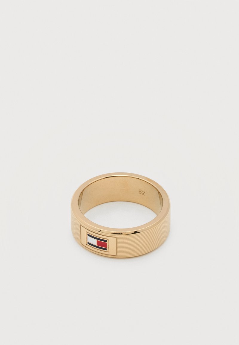 Anello in tonalità oro con superficie testurizzata e un emblema rettangolare della bandiera rossa, bianca e blu su sfondo bianco.