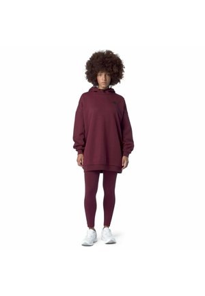 Felpa oversize bordeaux con cappuccio regolabile, logo nero e maniche lunghe, abbinata a leggings coordinati e sneakers bianche.
