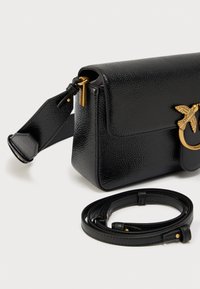 Μαύρη τσάντα από δερματίνη με υφή, με κλείσιμο με καπάκι, χρυσή λεπτομέρεια σε σχήμα πουλιού και ρυθμιζόμενο λουρί. Περιλαμβάνει αφαιρούμενο λουρί για ευελιξία.