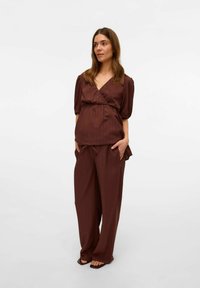 Ensemble brun en deux pièces avec un col en V, des manches courtes bouffantes et un pantalon à taille élastique. Le tissu a une texture subtile, une coupe décontractée et des poches avant.