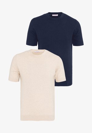 Deux pulls en maille à manches courtes et col rond, un bleu marine et un beige, présentés superposés sur un fond blanc.