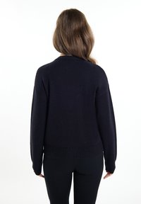 Granatowy sweter dziany z okrągłym dekoltem, długimi rękawami, ściągaczami na mankietach oraz ściągaczem na dole. Miękka tekstura, luźny krój, minimalny design.