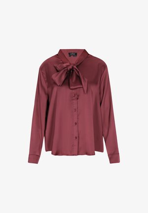 Burgundinpunainen satiinipusero, jossa solmittava kaulus, pitkät hihat, edessä napillinen suljenta ja sileä pinta. Mitoitettu istuvuus sivuhaaraolla.