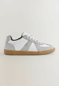 White and gray low-top sneaker with suede accents and gum rubber sole, shown from the side on a plain light background.