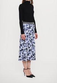 Černý rolák v kombinaci se sukní po lýtka s květinovým vzorem v modré a bílé barvě. Sukně má stříbrný elastický pas.