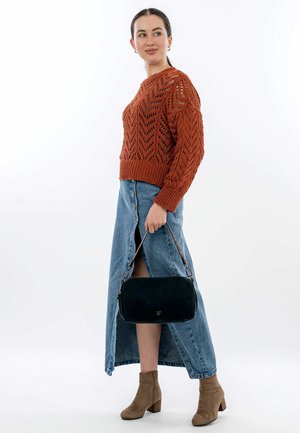 Maglione corto di colore ruggine in maglia aperta, abbinato a una gonna di jeans fino al ginocchio con bottoni e uno spacco laterale. Borsa nera e stivali alla caviglia color cammello.