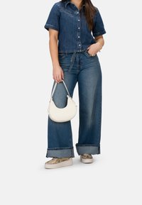 Denim-Hemd mit kurzen Ärmeln, hellblaue weit geschnittene Jeans mit umgeschlagenen Säumen und eine weiße runde Handtasche. Strukturiertes Schlangenhaut-Design Schuhe.