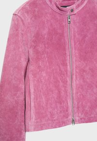 Veste rose à texture suédée avec une fermeture éclair argentée sur le devant et un col avec bouton-pression, montrant la manche gauche et le haut du torse.