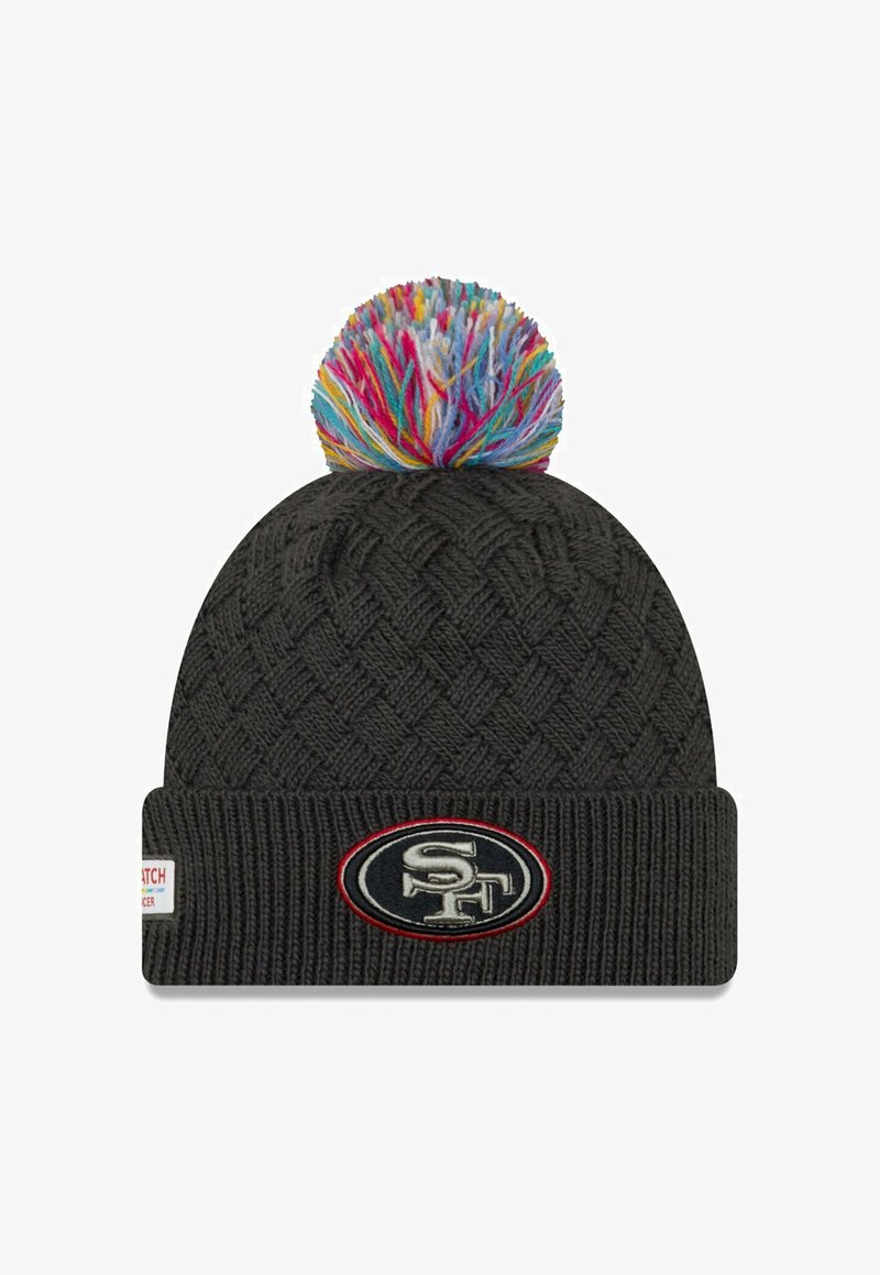 Bonnet tricoté noir avec un motif en diamant texturé, orné d'un pompon coloré sur le dessus et d'un patch circulaire au niveau du bord.