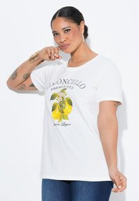 Camiseta de algodón blanca con un estampado gráfico de limones con hojas y flores, texto que dice "Limoncello Fresh & Juicy". Mangas cortas.