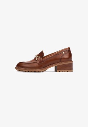 Mocasín de cuero marrón con una hebilla decorativa, tacón bajo tipo bloque, suela texturizada y costuras a lo largo de la puntera y los laterales.