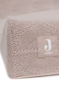 Geweven driehoekig kussen in zacht beige met een gebreid patroon en een klein label met een wit logo.