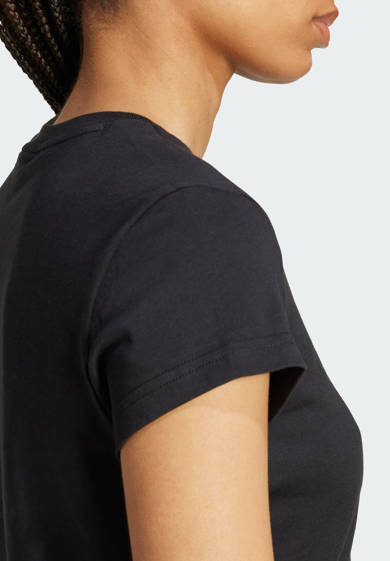 Schwarzes Baumwoll-T-Shirt mit kurzen Ärmeln, ausgestattet mit einem klassischen Rundhalsausschnitt und glatter Textur. Die Seitenansicht hebt das Schulternaht-Detail hervor.