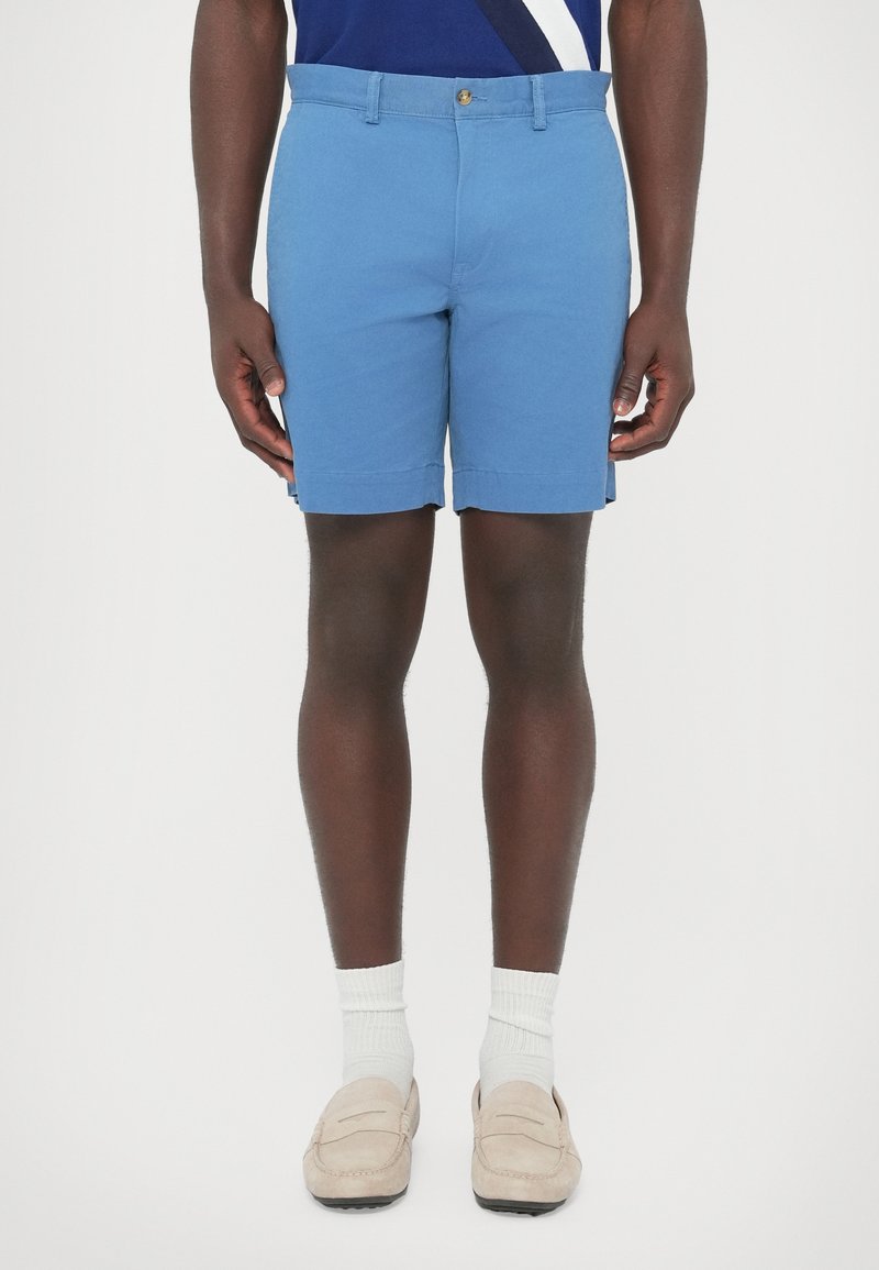 Svetlomodré šortky z bavlny, s klasickým strihom, štandardným pásom a jedným predným gombíkom. Hladká textúra, bez vzorov.