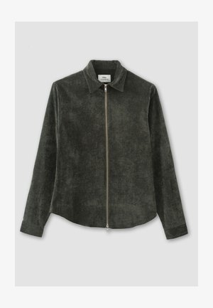 Veste chemise en velours côtelé vert foncé avec un col, des manches longues et une fermeture éclair à l'avant. Texture lisse avec de subtiles variations de couleur.